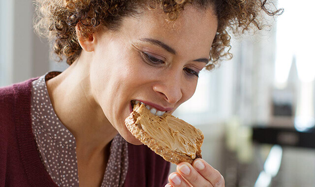 une femme mangeant un toast avec son appareil dentaire